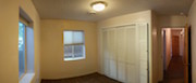 A panoramic view of the bedroom, hallway, and office door at the end of the hallway.  A full bathroom is between this bedroom and the office.